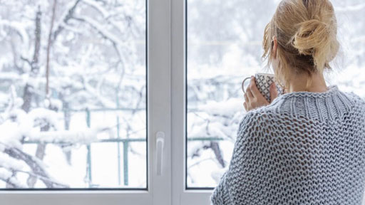 Woman enjoying comfortable climate in home while looking at snow outside